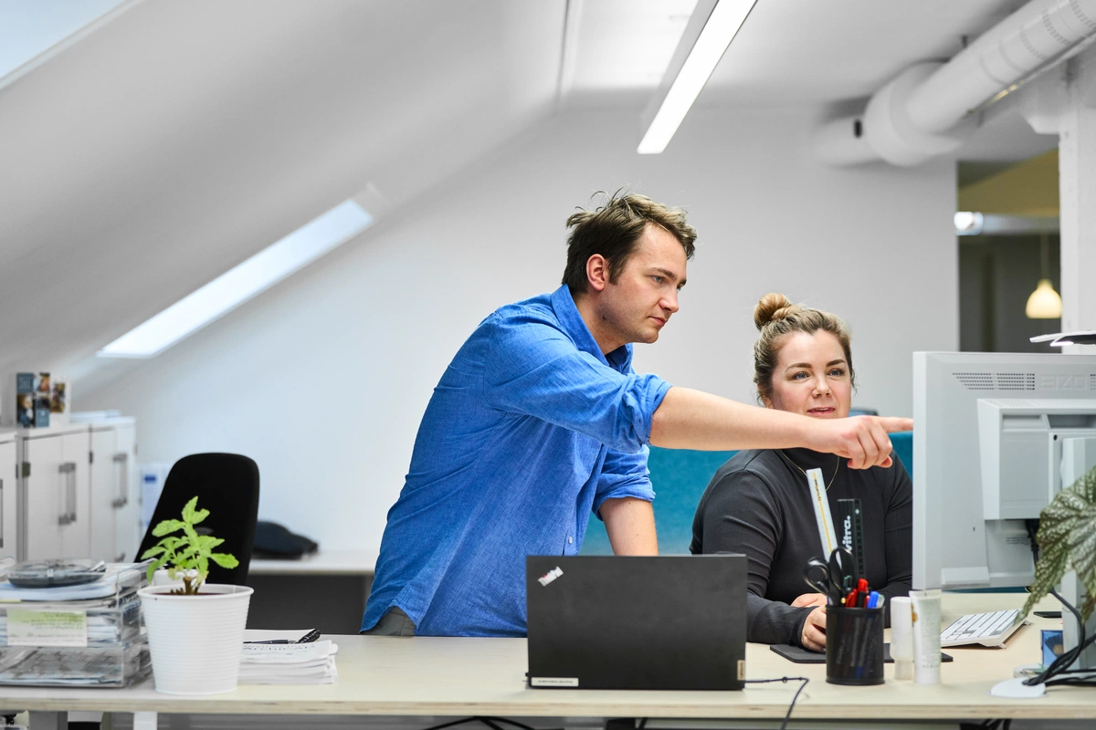 Dua arsitek sedang meninjau sebuah proyek di layar komputer di kantor mereka di Trondheim